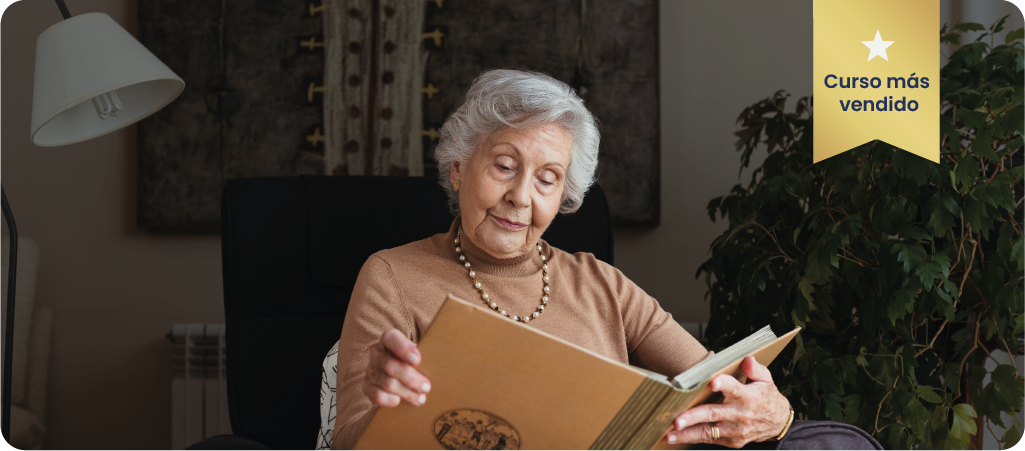 Portada del Curso de Alzheimer, en el cual aparece una señora mayor leyendo un gran libro de color marrón en el salón de su casa.