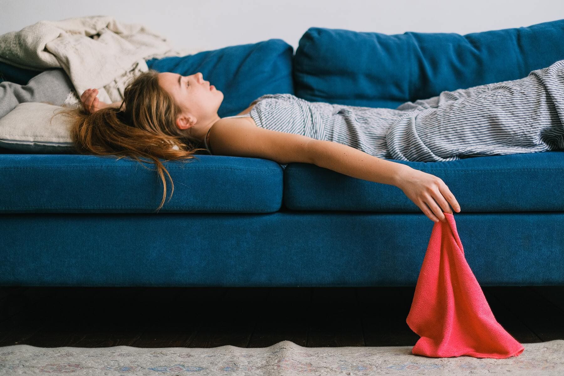 Una mujer se muestra cansada en el sofá tras limpiar. 