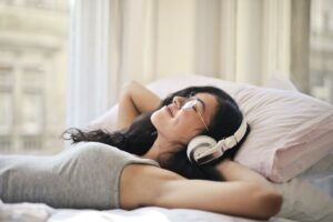 mujer tumbada en la cama escuchando música con cascos