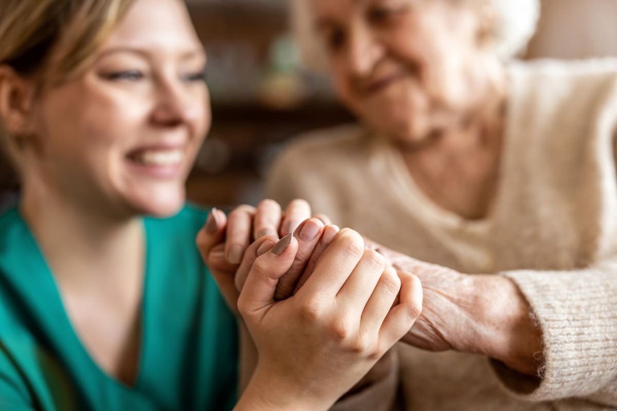 Mujer joven sujetando la mano de una anciana