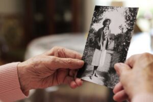 Manos de una anciana sujetando una fotografía antigua en blanco y negro: la demencia senil borra muchos recuerdos