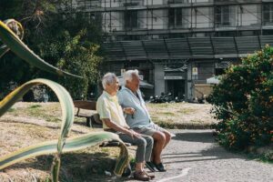 Dos ancianos socializan sentados en un banco de la calle