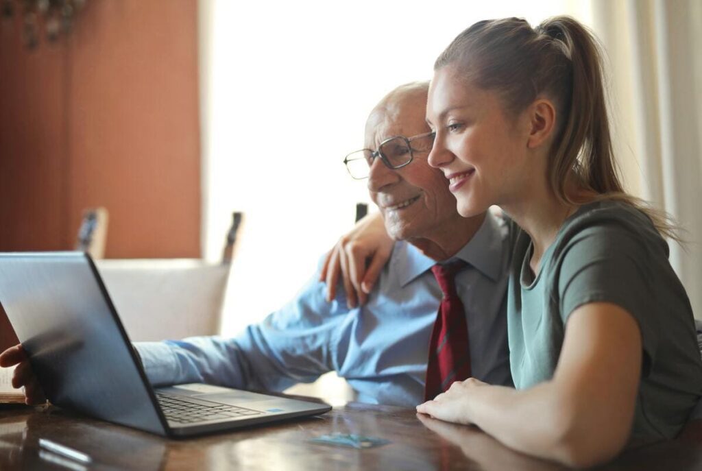 Mujer joven enseñándole a un anciano a utilizar el ordenador