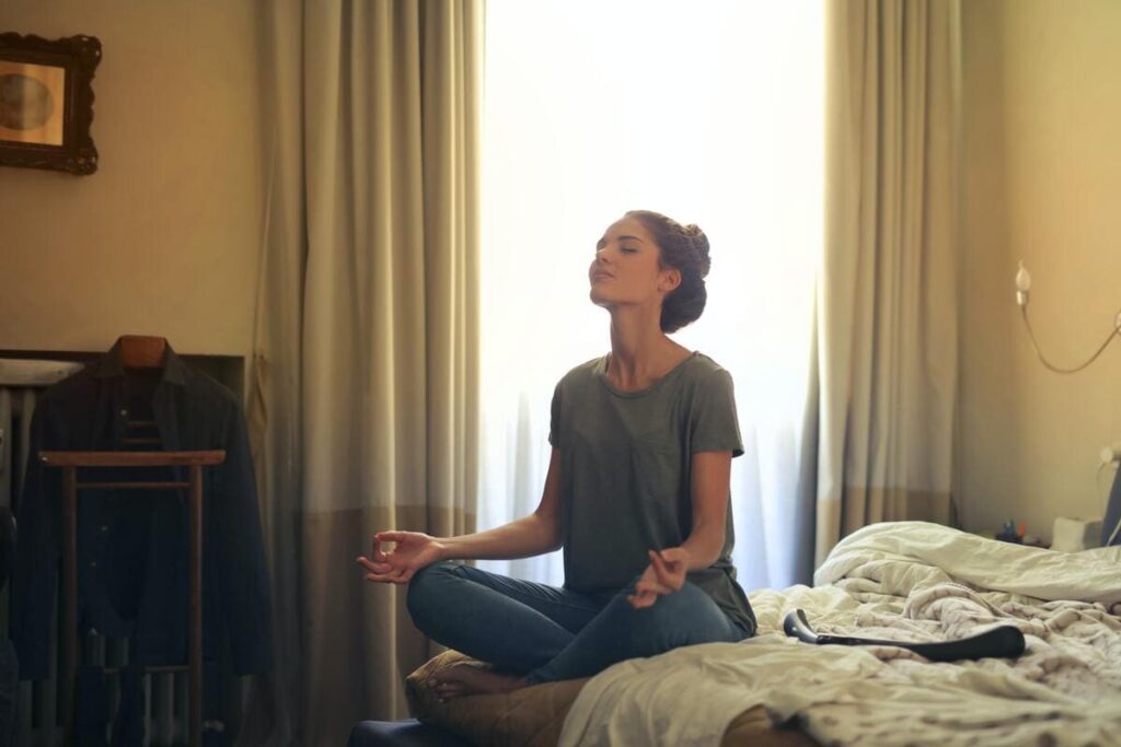Mujer joven practicando yoga como técnica de relajación y manejo del estrés en su habitación