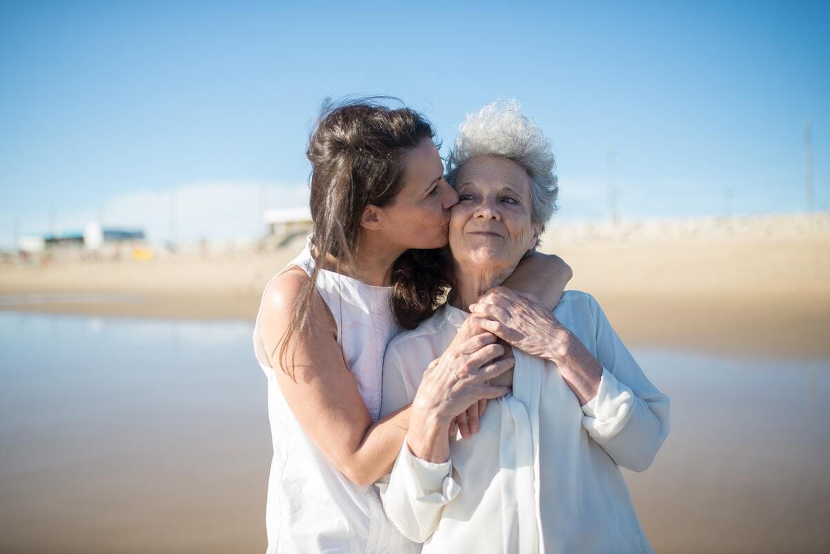 Ejemplo de atención psicosocial: mujer joven le da un abrazo a una mujer de edad avanzada