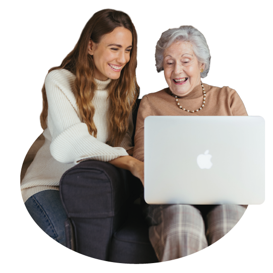 Una imagen recortada en silueta de una chica joven enseñando en un MAC algo a una señora mayor.