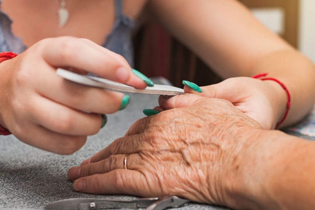 Cuidadora limando las uñas de las manos de una anciana