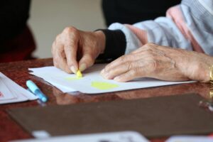 Detalle de las manos de una anciana coloreando sobre un papel con dibujos