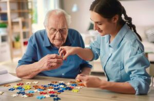 Una cuidadora juega con piezas de un puzle con un anciano en una casa.